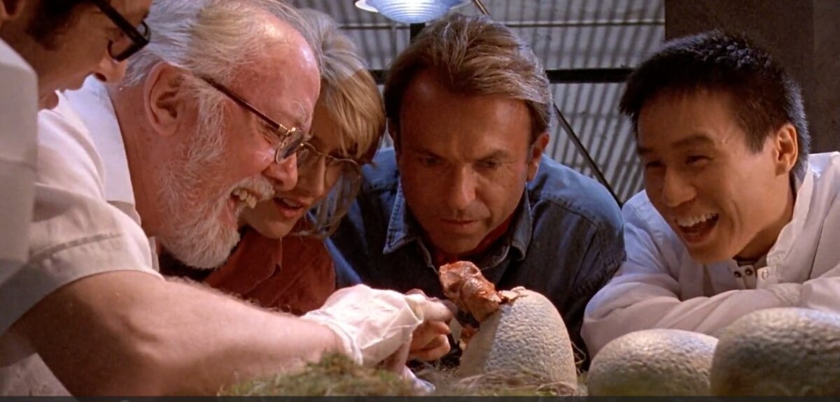 Hammond, Grant, Ellie, Wu, and Malcolm watching a baby dinosaur hatch in the lab